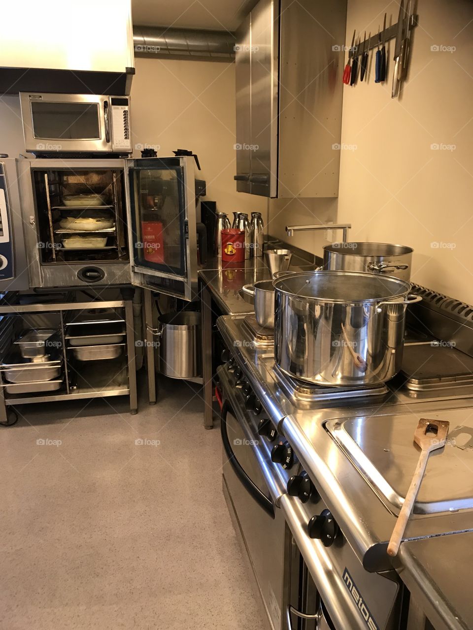 Fancy restaurant kitchen. Some baking ovens, boiling pans. Fancy shelves, and more kitchen stuff.