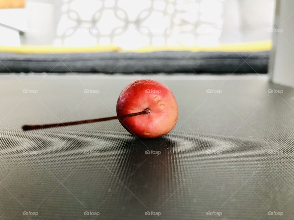 Pretty small red cherry fruit laying on grey table.