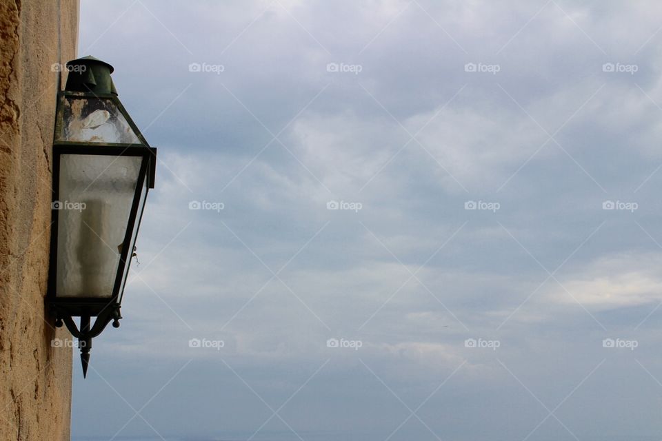 Old wall lamp, blue sky, clouds and plane 