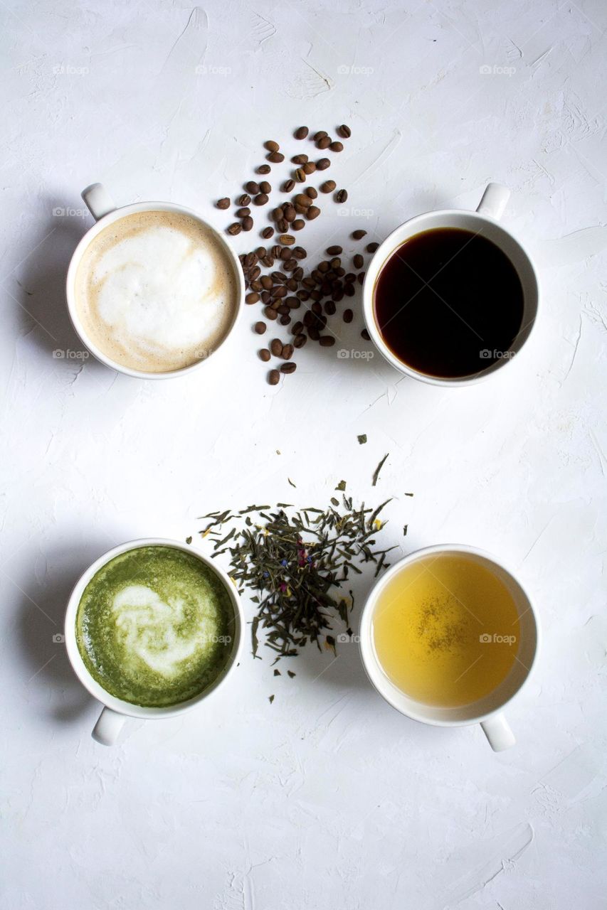 Four hot drinks  in cups, served with  tea and beans.