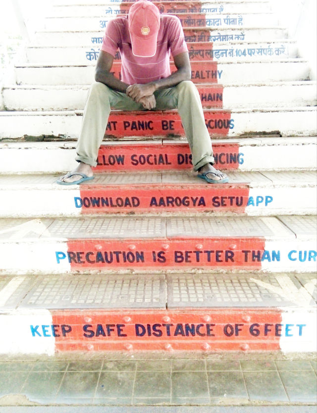 A photo of a man/a man sitting on a staircase/a photo of an Indian staircase/a man and a staircase photo/a troubled man sitting on a staircase/sample of natural photos/good real photo/good photo for you/without style photo