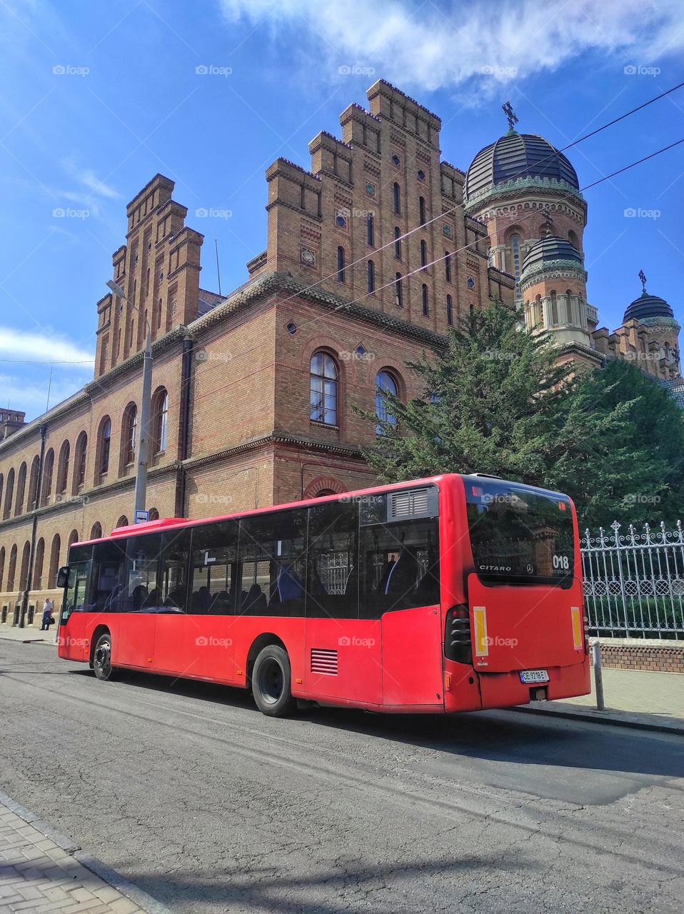 Red bus at the bus stop against the backdrop of the university