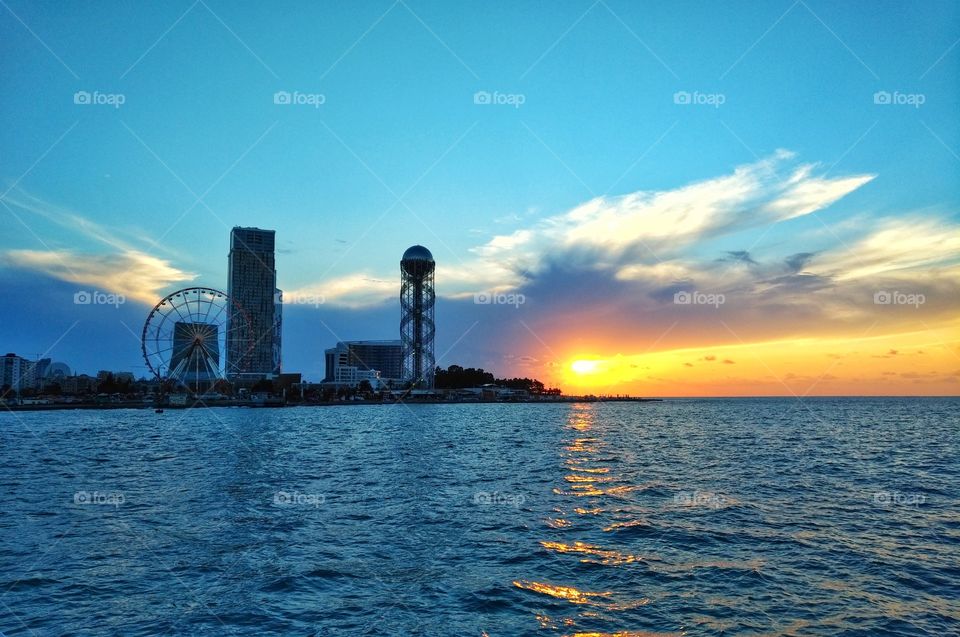 Panorama of Illuminated Resort city Batumi. Bright Evening Sky. View From Sea Beach To Illuminated Cityscape