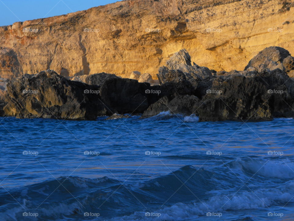 Yellow rocky cliff by the blue sea