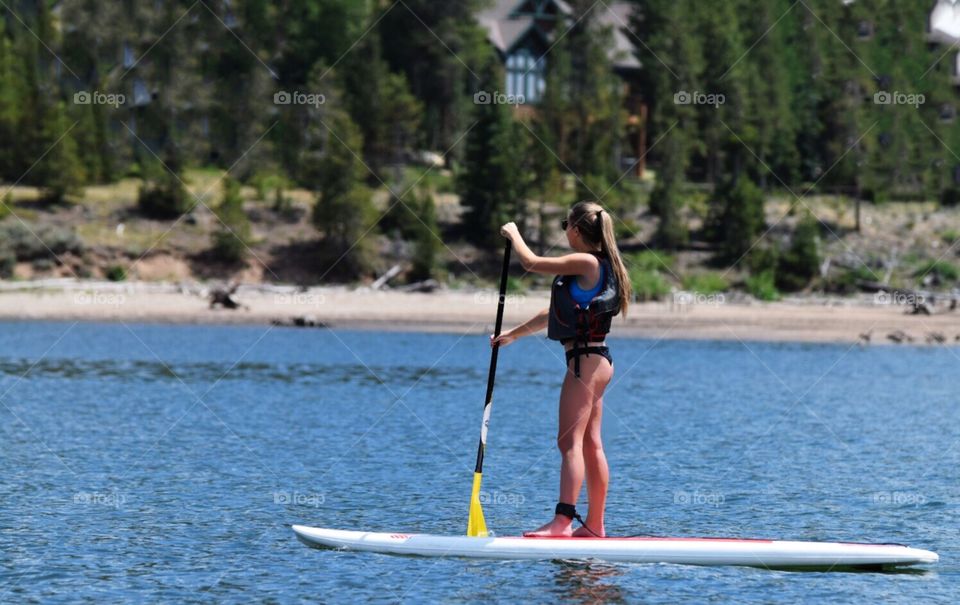 Young woman on a paddle board on a mountain lake