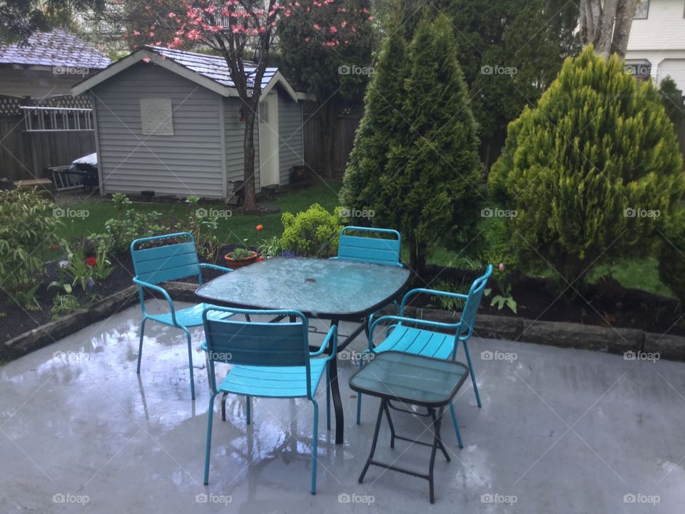 Rain down-pouring on table and chairs in the backyard garden 