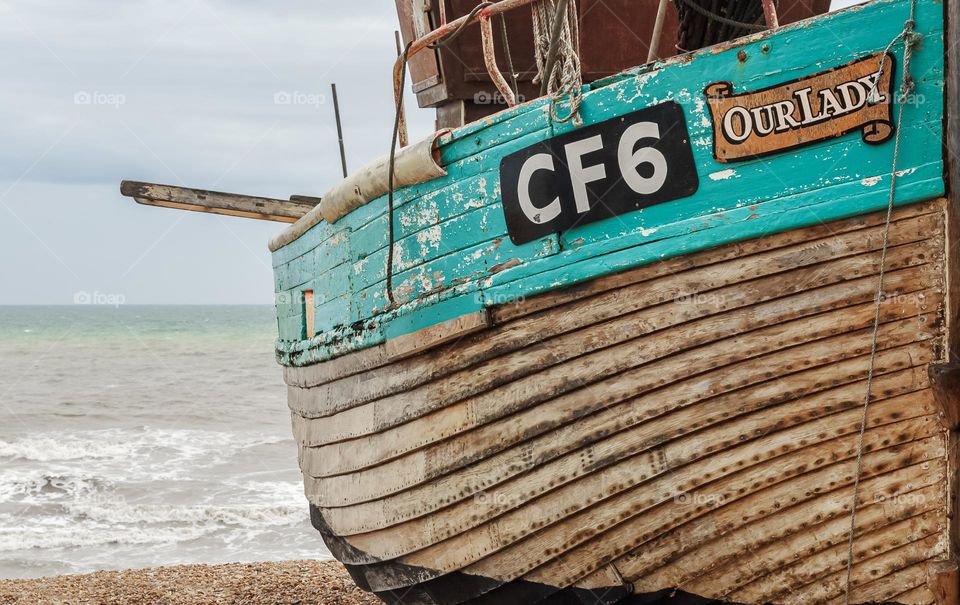 A wooden fishing boat “Our Lady” on a pebbled beach along the English Channel 