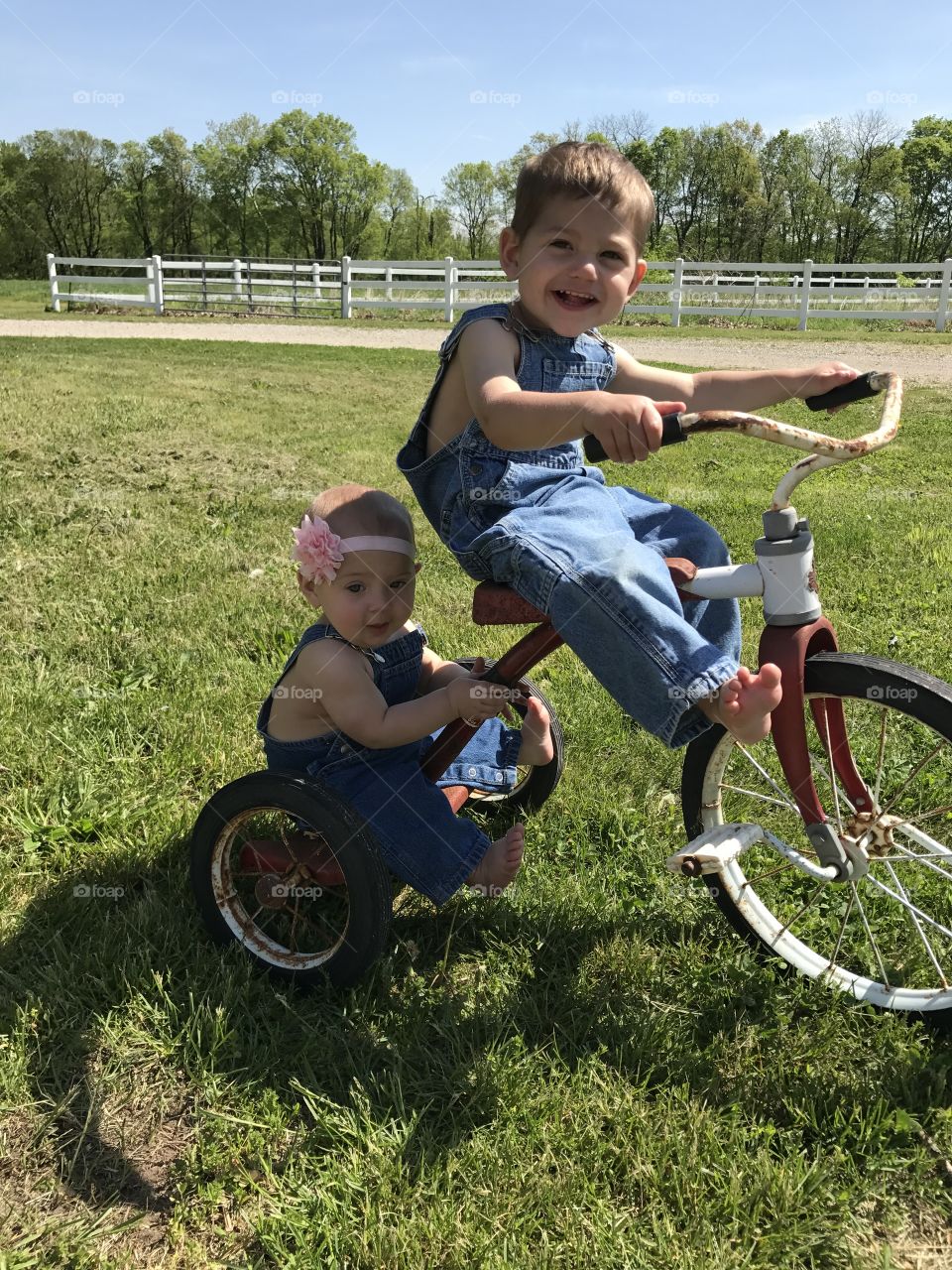 Country toddler siblings on antique bicycle 