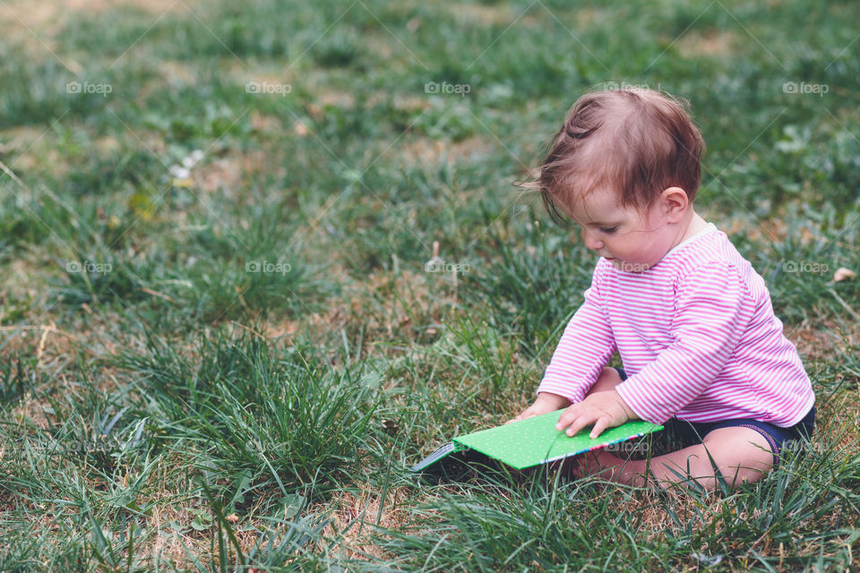 Little baby with a book. Little baby girl watching a book with pictures