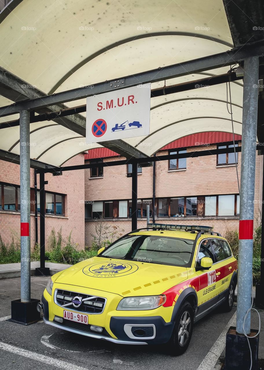 yellow ambulance car with a red stripe is parked at the designated S.M.U.R. and charged with electricity in the Erasme Hospital in Brussels, Belgium, close-up view. Ambulance concept.