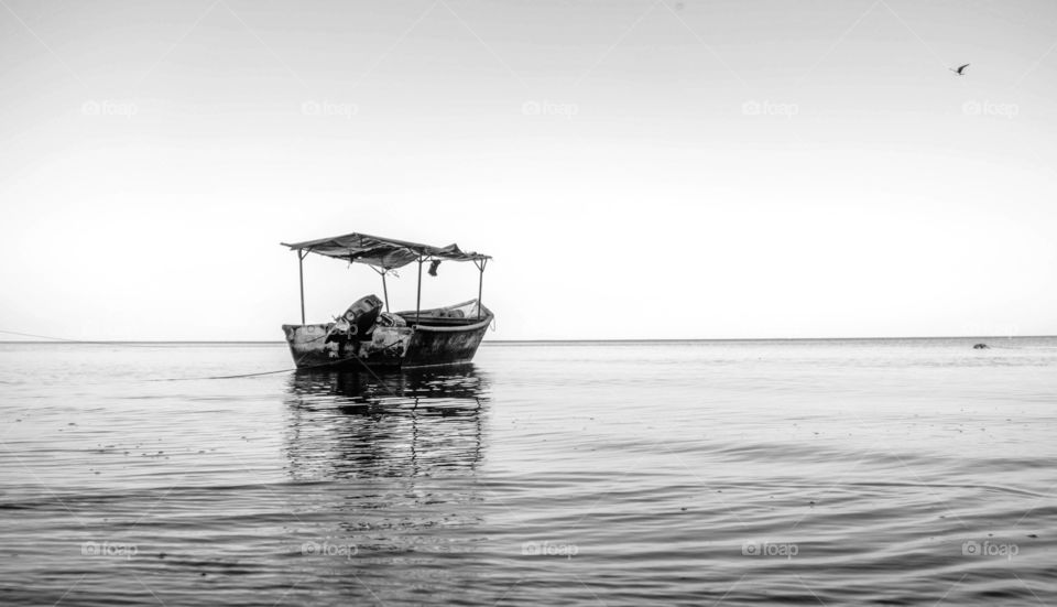 Composition of a fishing boat on the horizon between the sea and the sky