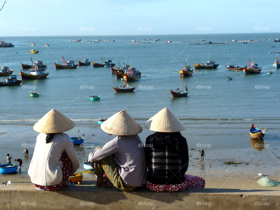 Women sitting with conical hat at beach side