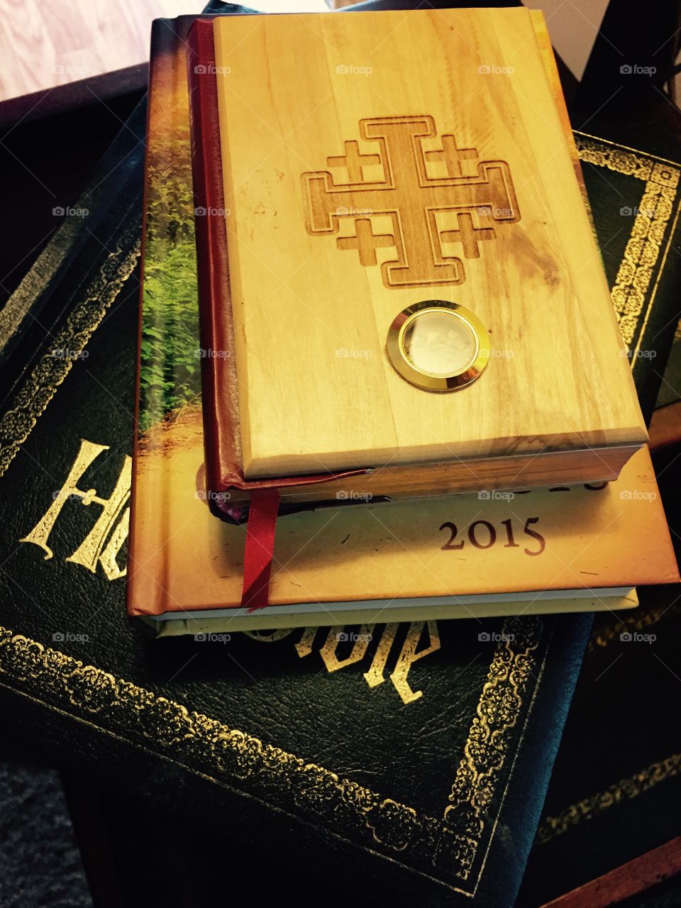 Two bibles on a stand with another book in between , stacked.