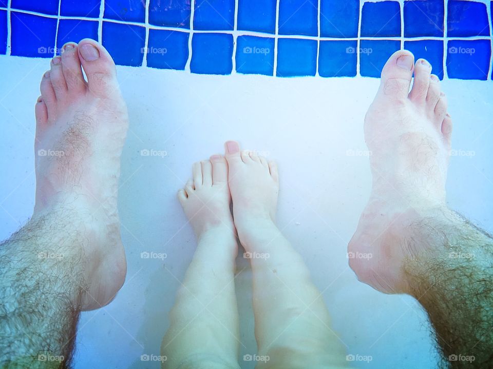 Father and daughter feet in the water