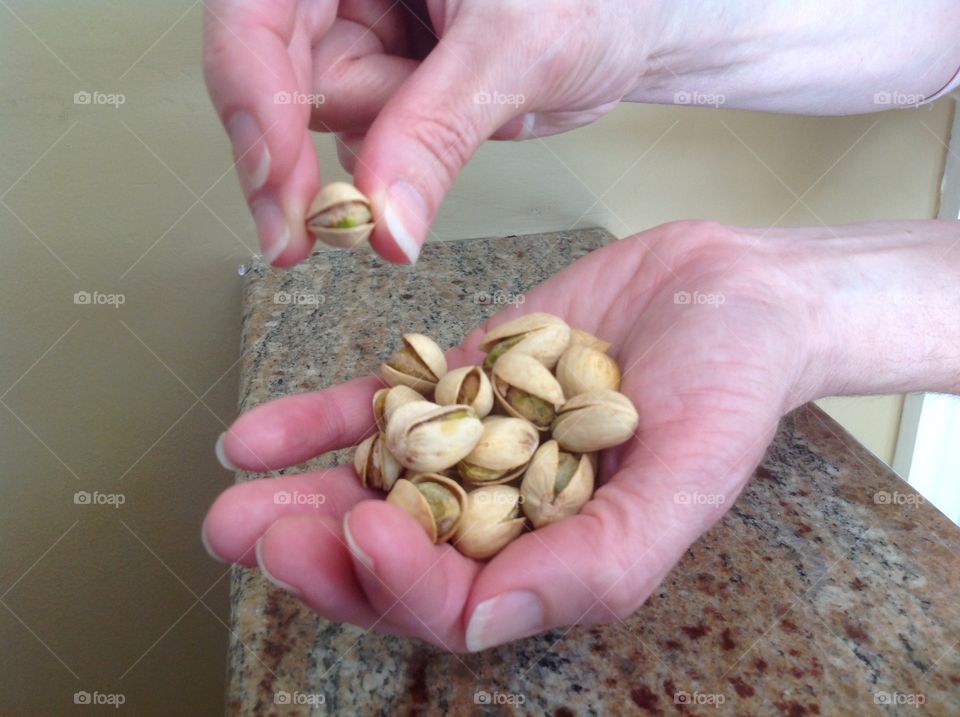 Holding a handful of pistachio nuts.