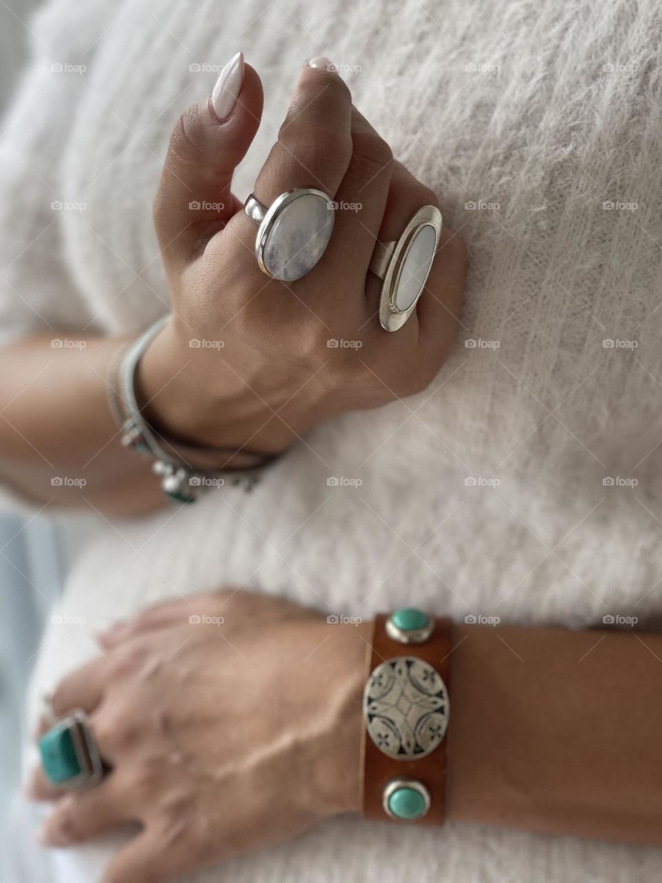 Woman’s arms and hands wearing various semi precious stones rings and bracelets 