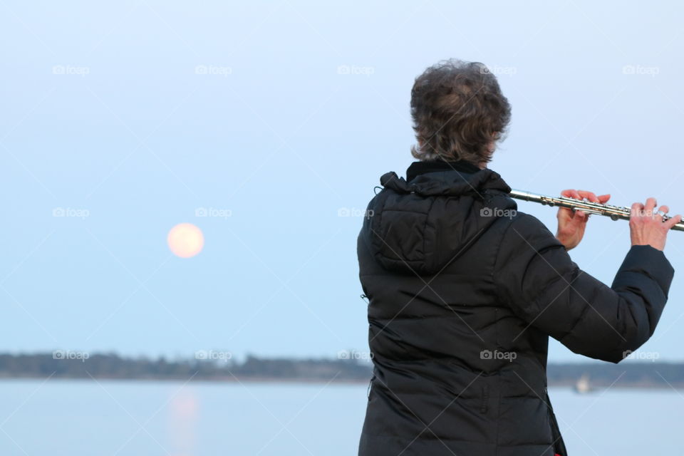 Woman playing flute on moonrise 