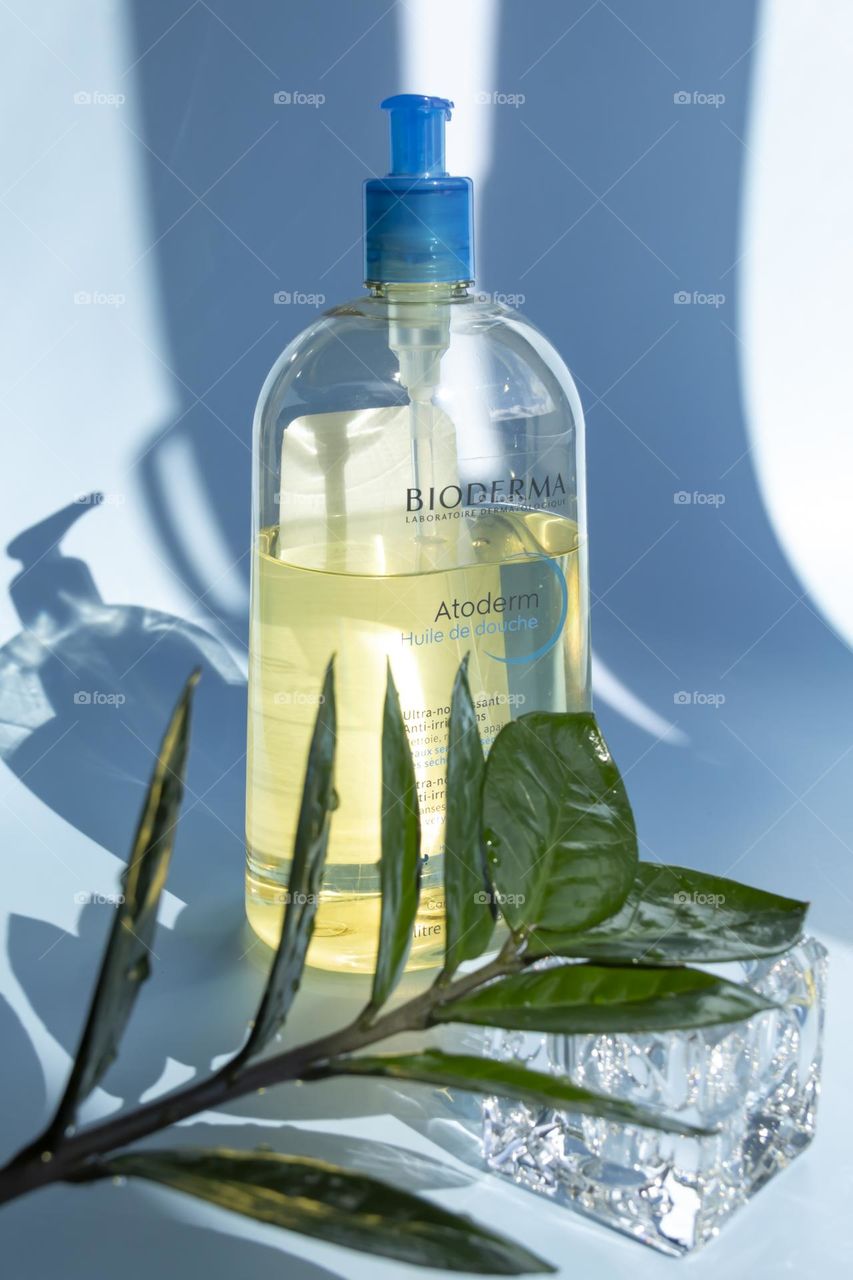 Cosmetic product Bioderma for skin care on a blue background, with a green flower.