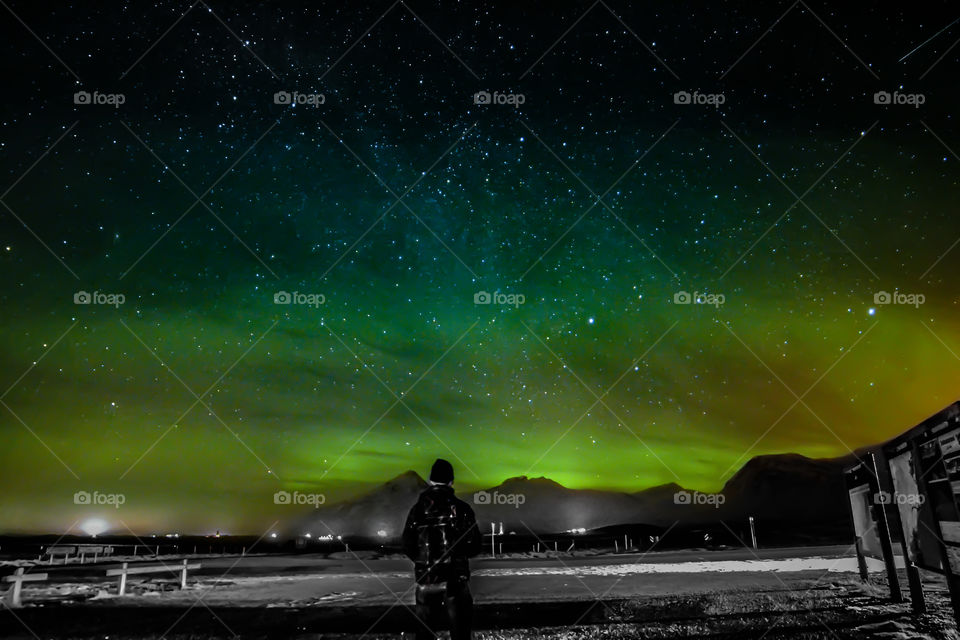 Man silhouette observing aurora borealis extending over mountain range in Iceland