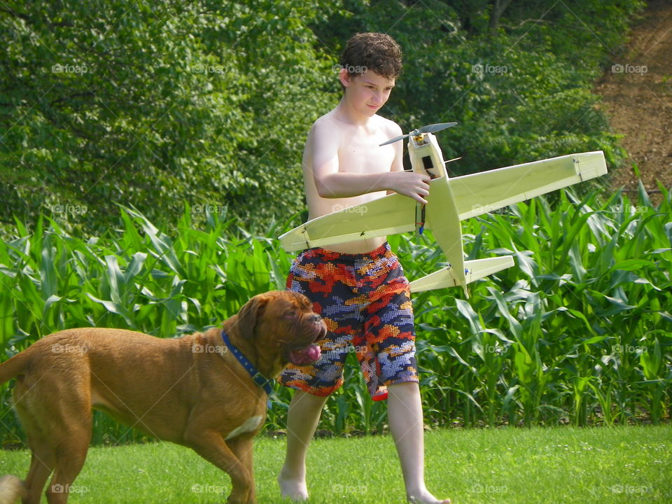 Boy playing with airplane and dog