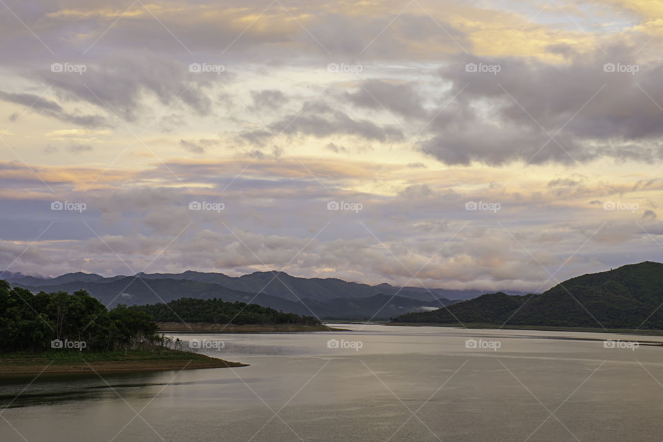 The reflection of the Sun and the clouds on the sky Background mountain and water at Kaeng Krachan dam in phetchaburi , Thailand.