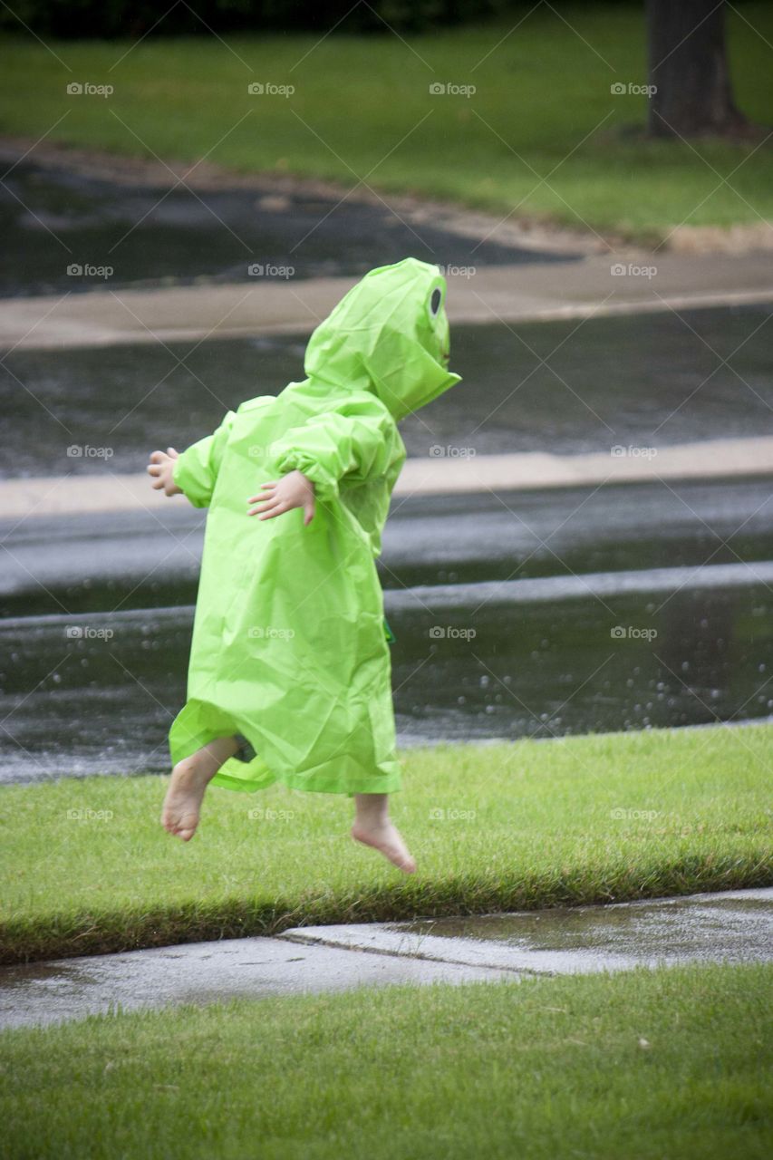Boy jumping in a puddle during rainy