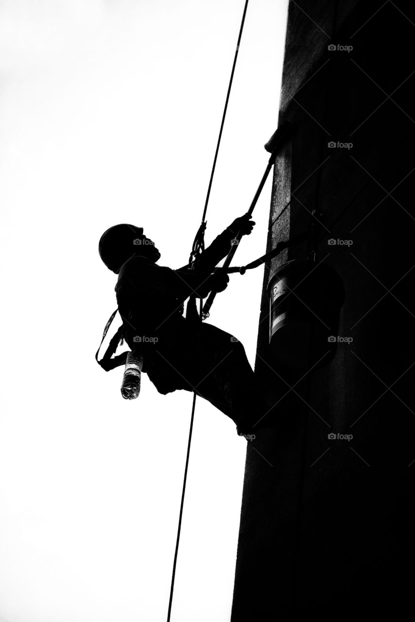 Silhouette of worker abseiling down side of a tower block in Kuala Lumpur Malaysia
