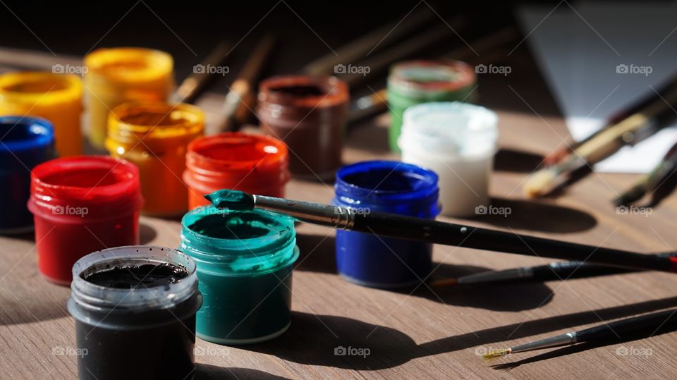 Paintbrush on watercolor paints on table