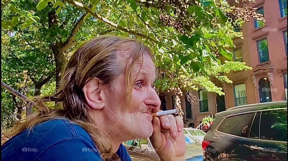 My life partner for nearly 16 years, “Timothy Trespas” is enjoying his cigarette sitting on our favorite stoop on “Waverly St” off “Fulton St” in “Clinton Hill”, Brooklyn. This city block has lots of lush green vegetation. 2022. Hypnotic Productions