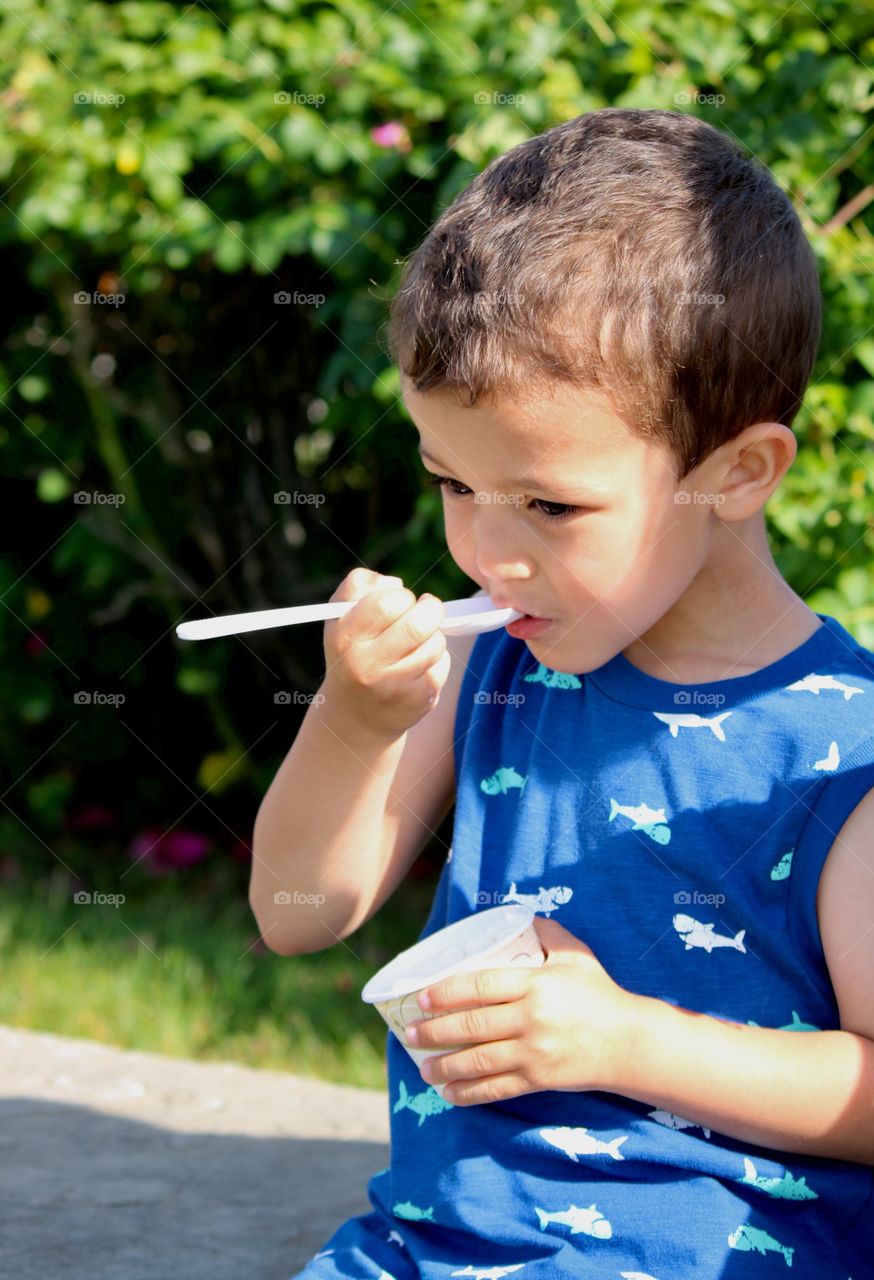Child enjoying a cup of ice cream on a hot June day