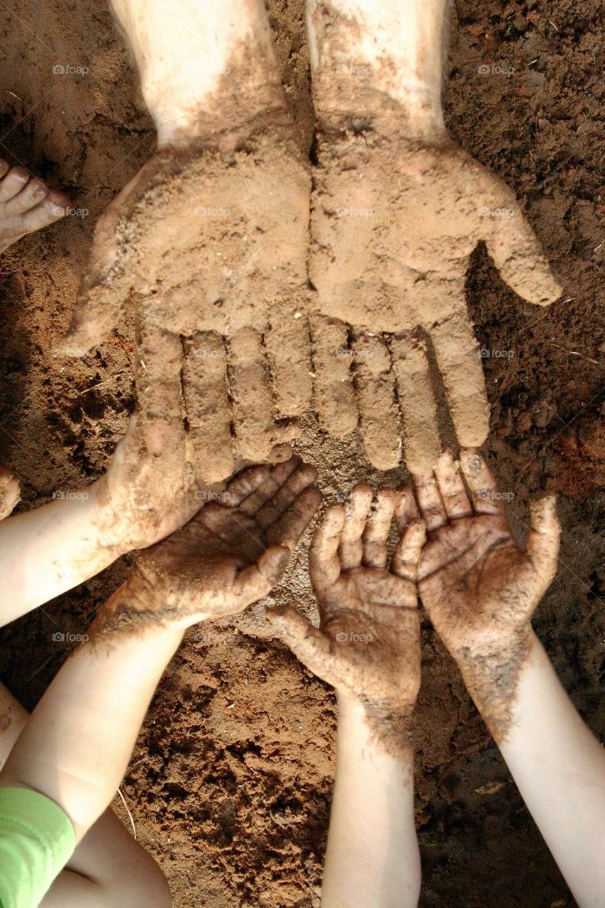 Father and sons hands full of mud after planting together