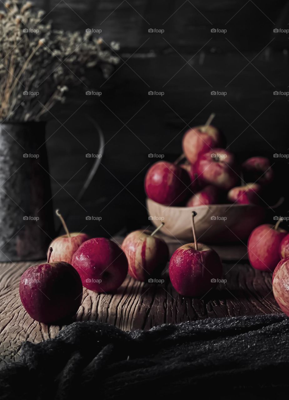 Red apples on a wooden table and in wooden bowl with vintage mood and dark background 