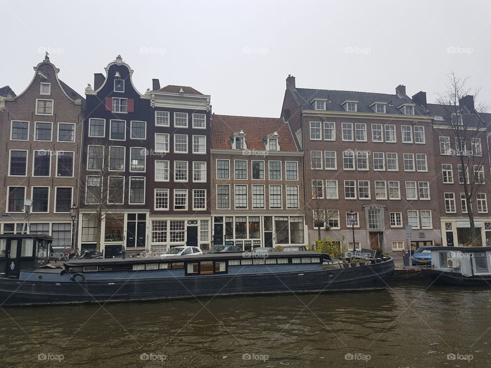 Vintage architecture roofs on buildings on an old alley street along canal and boat in Amsterdam, Holland, Europe.