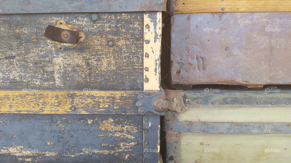 A close view of the the corners of four antique trunks stacked on top of each other.