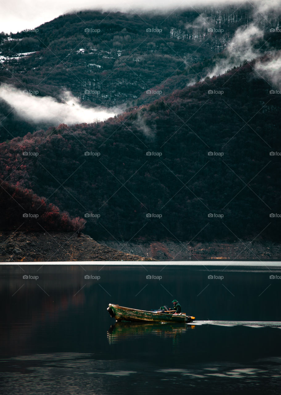 Man on a boat in a lake in the mountains