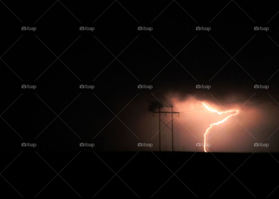Lightning and power pole in black sky