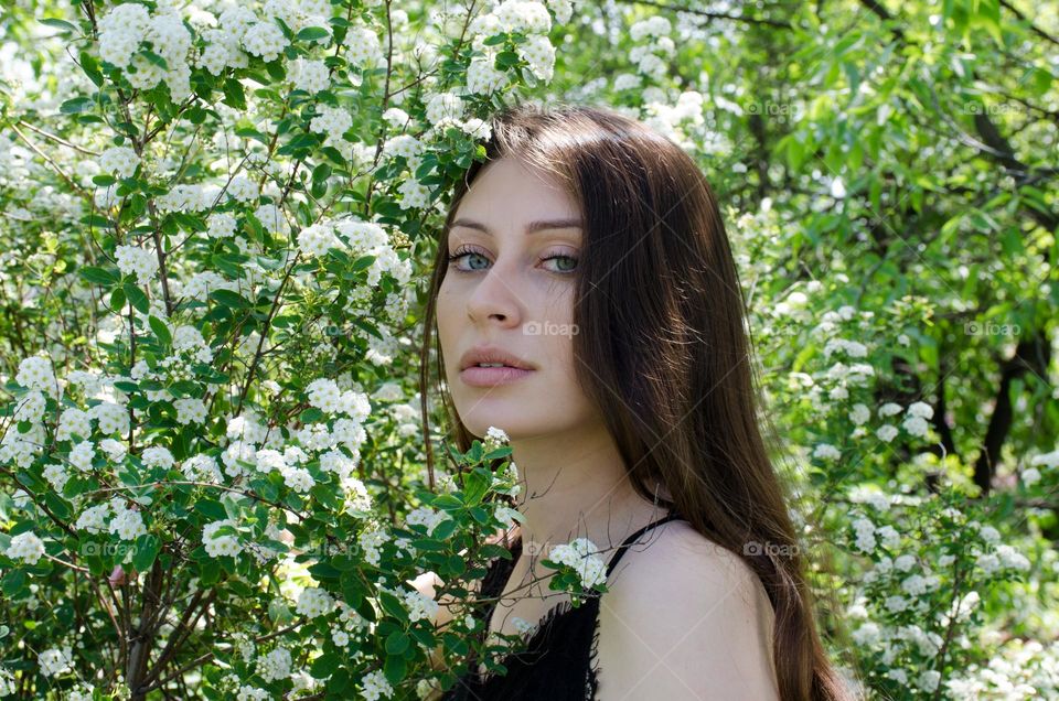 Portrait of a Beautiful Young Girl on Background of Flowers