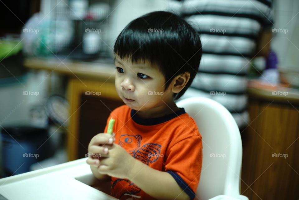 Asian boy eating on baby seat