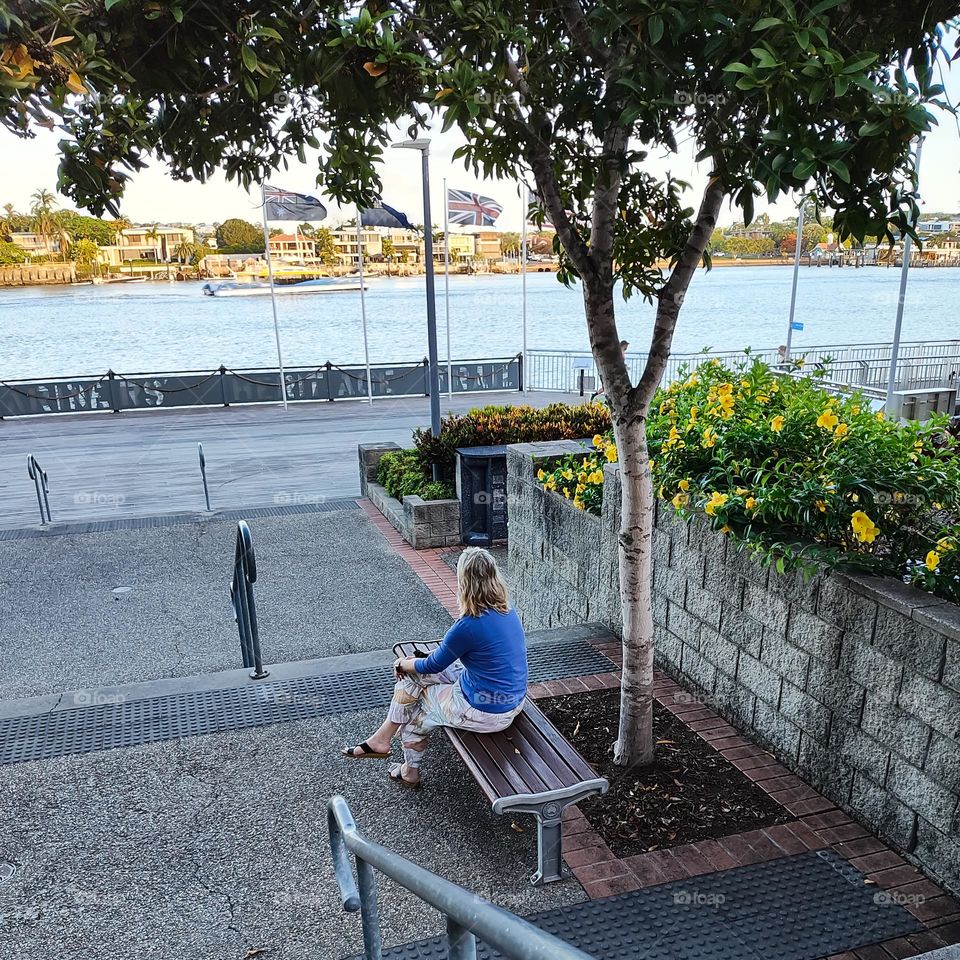 Woman sitting alone on a bench over looking river