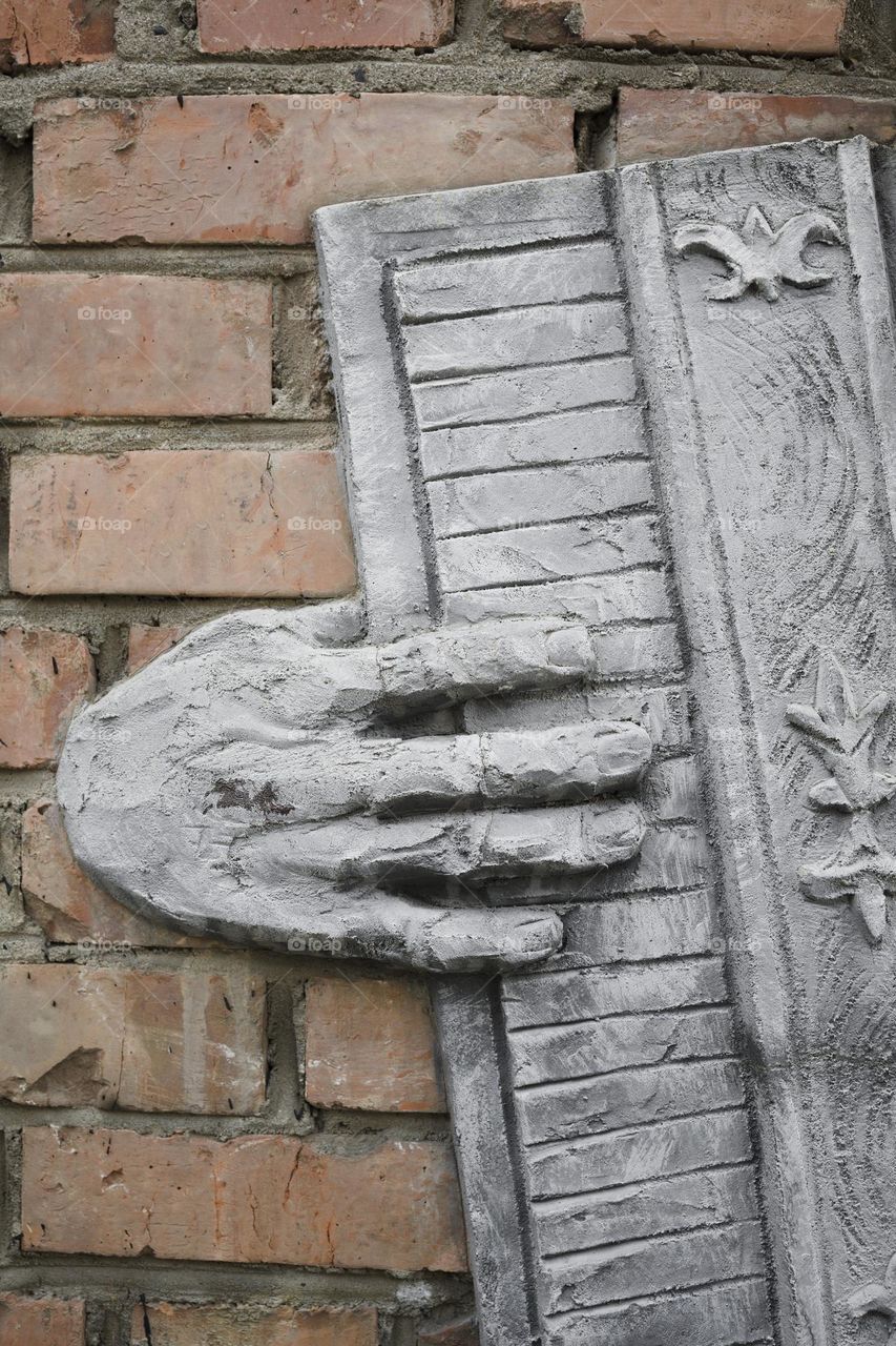 Vertical shot of an accordion sculpture on brick wall