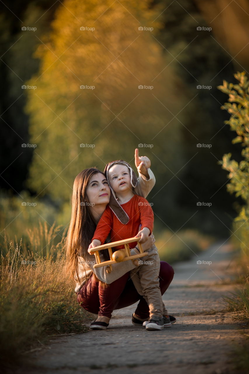 Mother and son with wooden plane at sunset