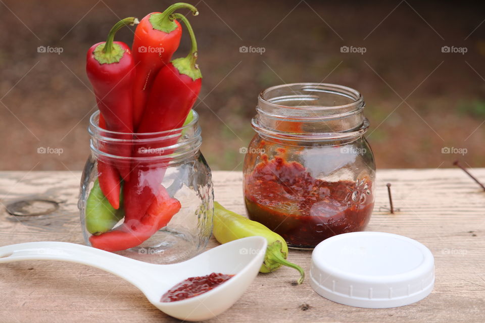 Fresh red peppers capsicum; homemade chopped pepper preserves; outdoor rustic farm image blurred background 