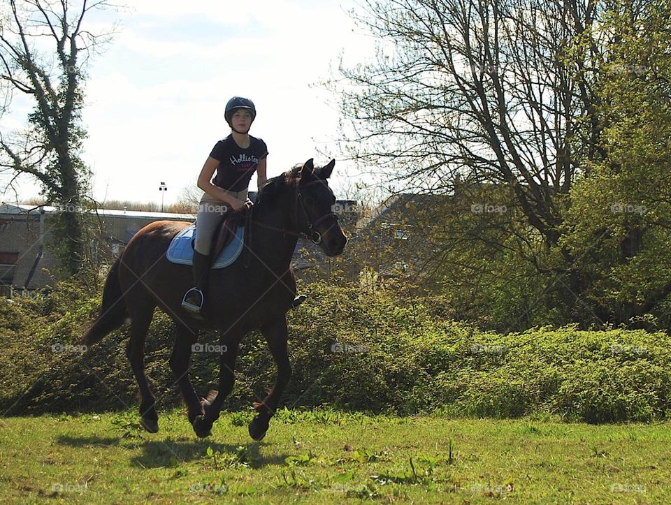 A girl and her mare galloping in a field in France during summer 