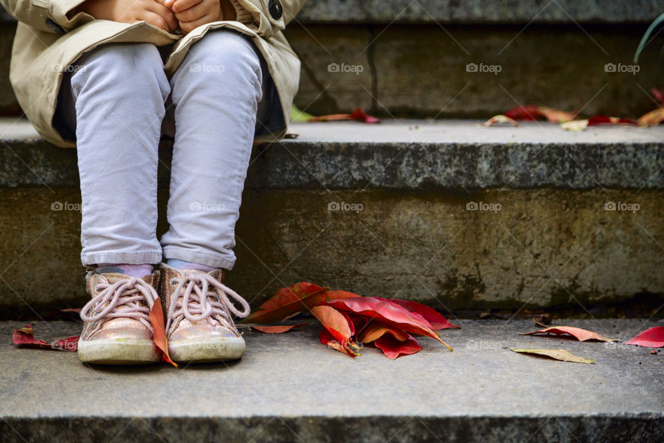 Stylish little girl sitting on the stair in autumnal park