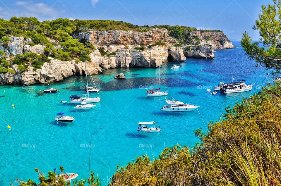 amazing cala macarella beach view with yachts, boats and beautiful rocks and turquoise water - menorca balearic island
