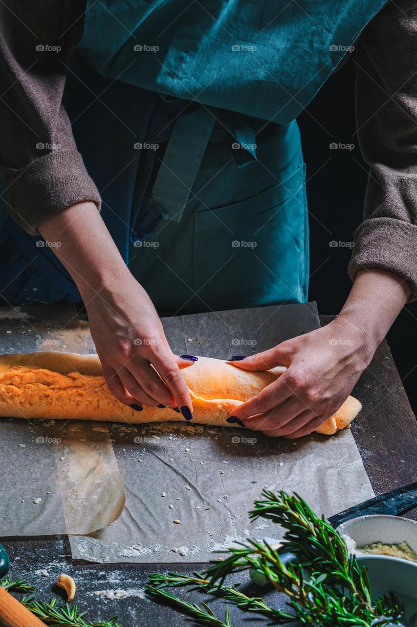 Women's hands, flour and dough. Levitation in a frame of dough and flour. A woman in an apron is preparing dough for home baking. Rustic style photo. Wooden table, wheat ears and flou.Emotional photo