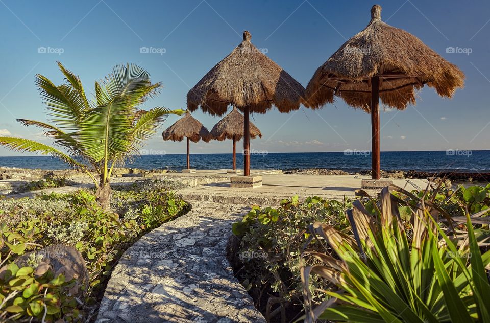 Umbrellas of a bathhouse on the rocky coast of the Mayan riviera in Mexico at Puerto Aventuras.