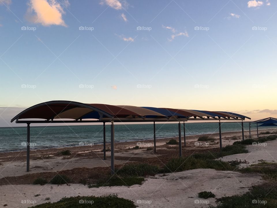 Pergola sun shade on tropical beach at sunset