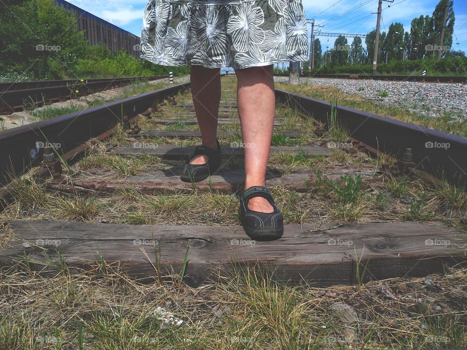 woman's feet on the railroad tracks