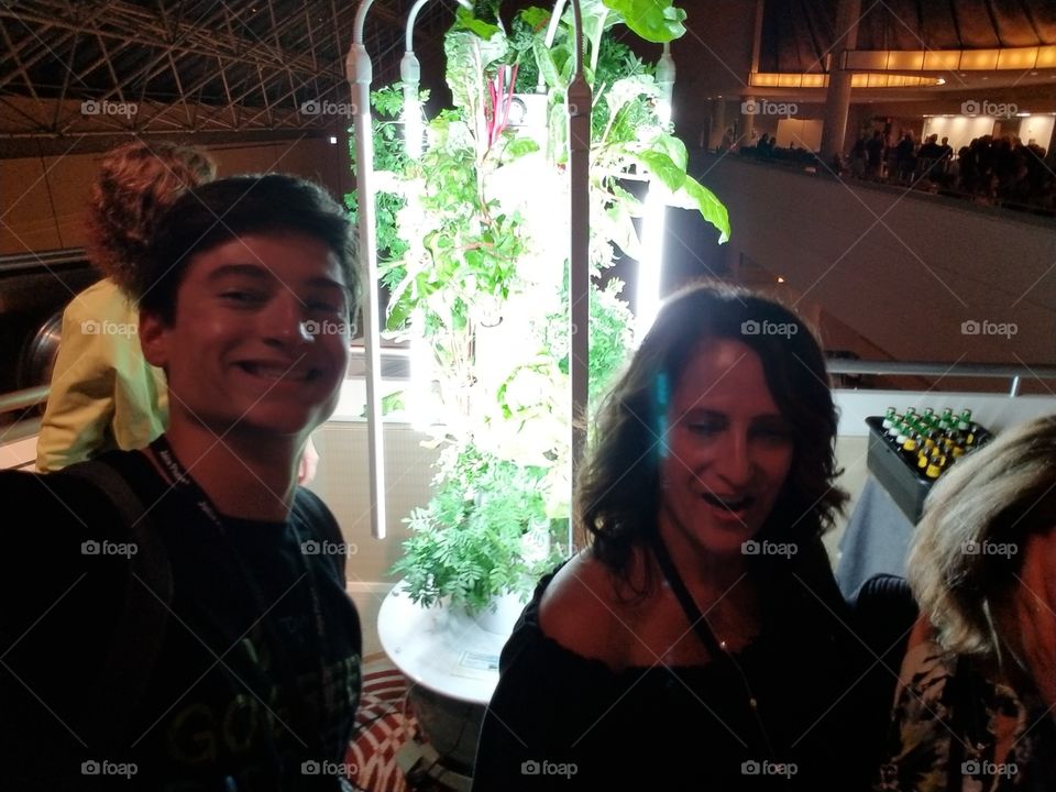 this is me and my mom at a conference. there's a vertical tower garden behind us. eat your greens.